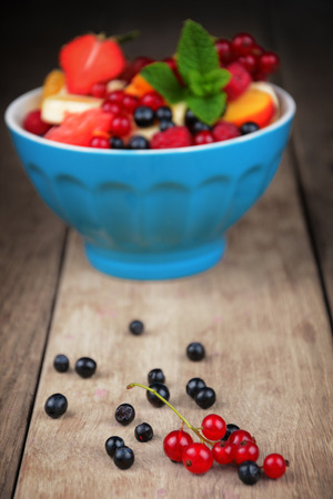 Fresh tasty fruit salad in the bowl on the wooden tableの写真素材