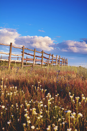 Fence in the green field under blue cloud sky. Beautiful landscapeの写真素材