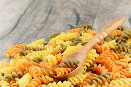 Raw eliche tricolori pasta background on the wooden tableの写真素材