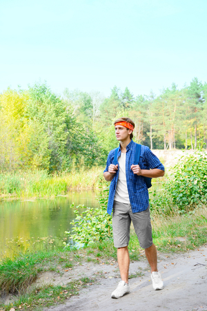 Young beautiful man is hiking in the forestの写真素材