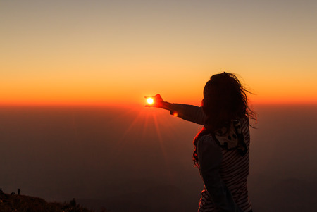 Woman as Silhouette and Hand holding the Sun の写真素材
