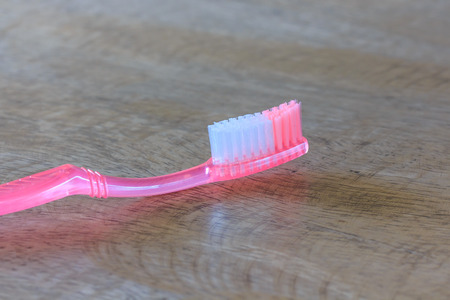 Closeup on a Pink Tooth Brush on Wooden Background 