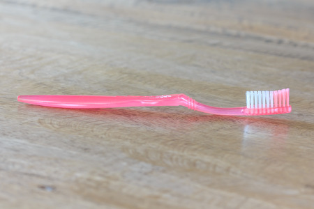 Closeup on a Pink Tooth Brush on Wooden Background の写真素材