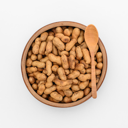 Roasted peanuts in wooden cup, top view isolated on white background.の写真素材