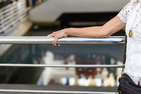 Old woman hand touching a metal banister.