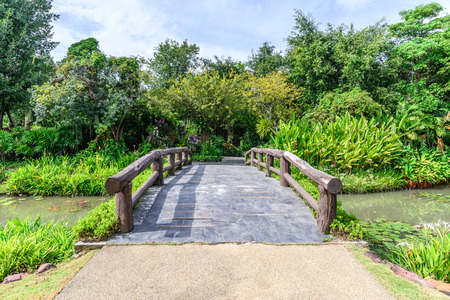 Cement bridge with wooden balustrade over pond to garden.の写真素材