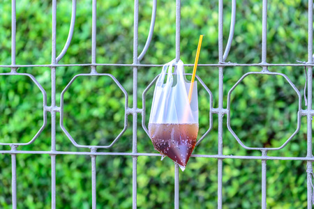 Platic garbage, plastic bag used for sparkling water was left on fence in city.の写真素材