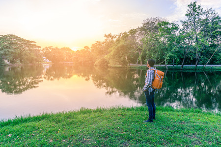 Man hiker standing near beautiful lake at sunset.の写真素材