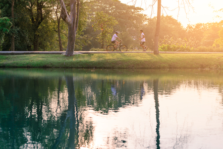 Motion blured of people are running and cycling in urban park with water reflection.の写真素材