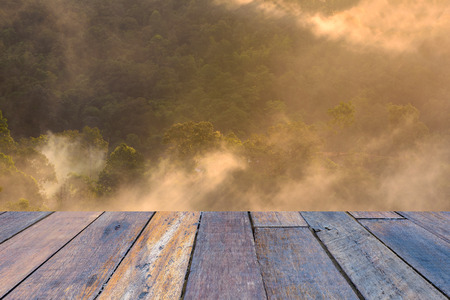 Morning mist with mountain at sunrise with wooden floor perspective.の写真素材