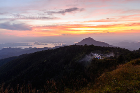 Campfire smoke from camping site at beatiful place, mountain peak at sunnset.の写真素材