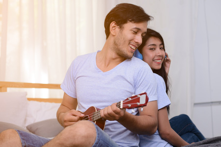 Couple relaxing together with ukulele and listening a song.の写真素材