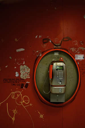 Public phone on a red graffiti painted wallの写真素材
