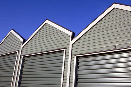 A row of uniform garages with roller doors on a blue sky background の写真素材