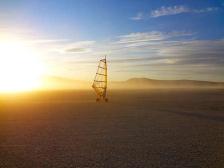 A single land wind surfer on a remote dry lake bed.                               