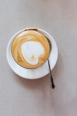 A cup of latte art coffee with heart shape on table in top view.の写真素材