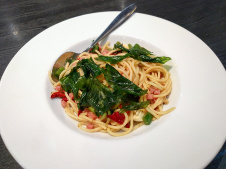 Spaghetti bacon with crispy basil leaves in white plate in restaurant.の写真素材
