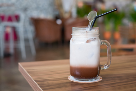 Iced chocolate with milk in retro glass jar (Mason Jar) on wooden table in cafe.の写真素材