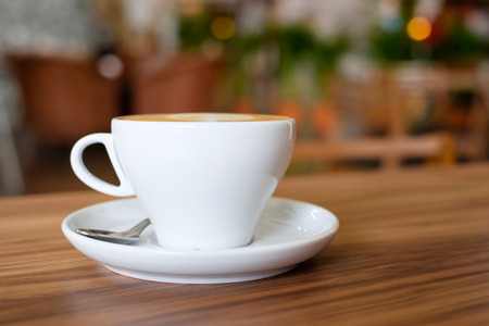 A white mug cup containing hot coffee on wooden table in cafe.の写真素材