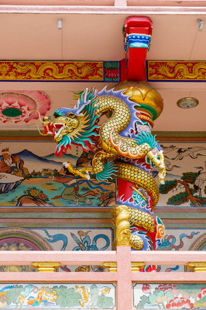 Golden Chinese dragon Wrapped around red pole at Chinese temple bacony.の写真素材