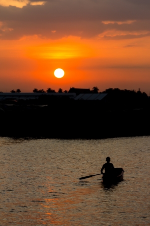 Rowing man in boat at sunsetの写真素材