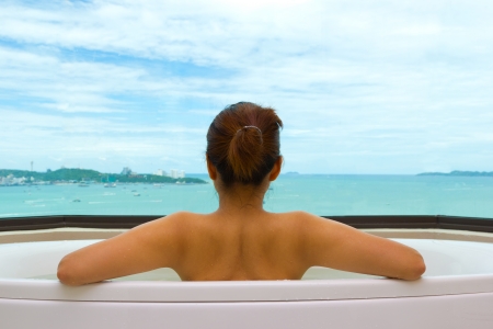 Backside woman in bathtub on sea viewの写真素材