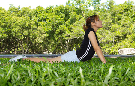 Young women exercise yoga with horizontal on grassland の写真素材