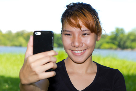 Asian women taking pictures of themselves with a cellphoneの写真素材