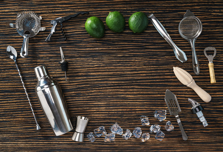 Wooden counter with fresh limes, ice cubes and bartending tools.の写真素材