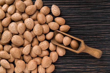 Almonds with nutshell in brown bowl on textured wooden background, top view.の写真素材