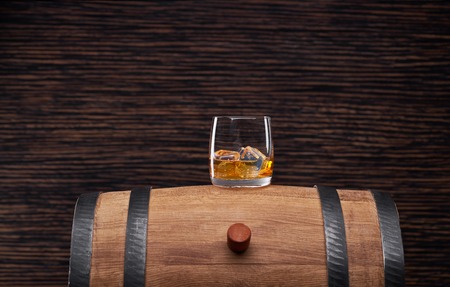 Single shots of whiskey  with ice  on a traditional oak barrel
