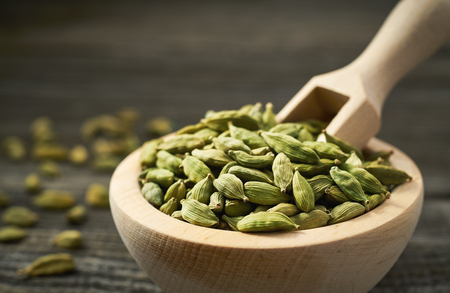 Cardamom  in a wooden scoop . Cardamom  in a wooden shovel  on a gray wooden background.の写真素材