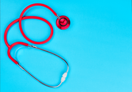 Red stethoscope  on blue table background with copy space for  text. Medicine conceptの写真素材