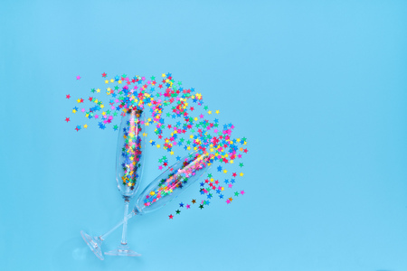 Two champagne glasses with colorful confetti  on blue background. Top viewの写真素材