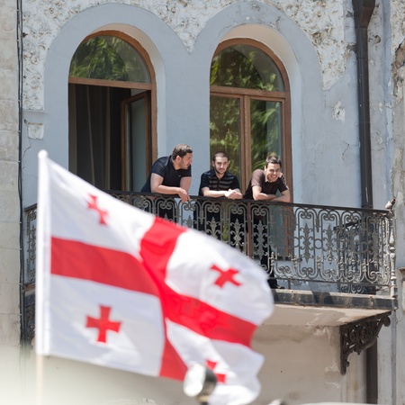 TBILISI - MAY 26: The Independence Day of Georgia. Young men watch military parade from old building balcony. May 26, 2010 in Tbilisi, Georgia.のeditorial素材