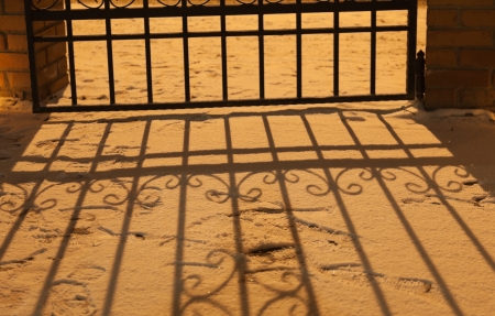 Shadow of fence on snow in orange street light at night. Russia.の写真素材