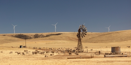 Old broken wind pump and new wind generators distorted by hot air  South Australia の写真素材