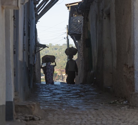 HARAR, ETHIOPIA - DECEMBER 23, 2013  Unidentified women carry things on their heads in narrow alleyways of ancient city of Jugol のeditorial素材