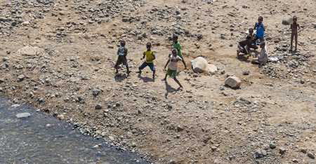 NEAR KONSO, OMO VALLEY, ETHIOPIA - JANUARY 3, 2014: Children dance on a dry riverbed in a school break.のeditorial素材
