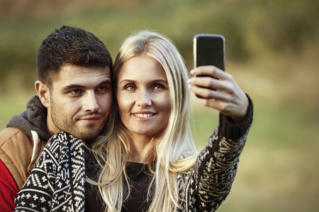 Hiking couple. Active young couple in love. Couple taking self-portrait picture on hike. Man and...