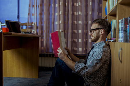 Student working hard over night in library going through books. Smartly dressed handsome man with stuck of books around him in his office,の写真素材