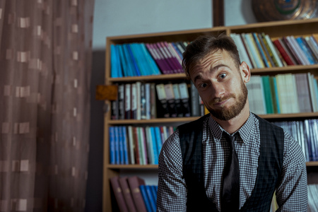Student working hard over night in library going through books. Smartly dressed handsome man with...