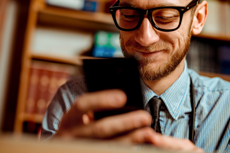 Doctor Observing X-Ray at his Office and using the smartphone. Dramatic scene vivid contrast colorsの写真素材