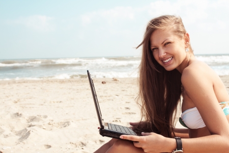 Sexy beautiful woman in bikini using laptop at the beachの写真素材