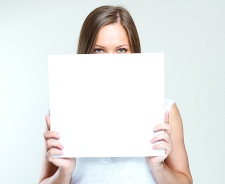 smiling happy woman holding  blank paper. empty copyspace for ads.の写真素材