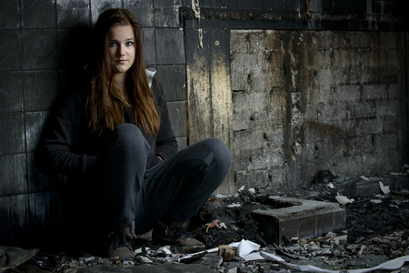 Portrait of a young girl sitting in a house what has been destroyed by fireの写真素材