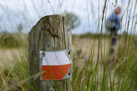 red white trail hiking pointer on a wooden pole in the grassの写真素材