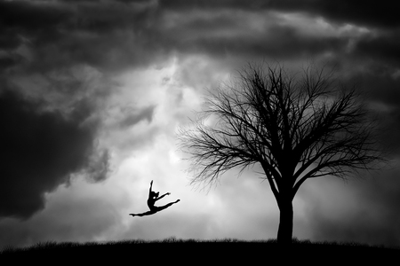 silhouette of a ballerina and a tree in a stormの写真素材