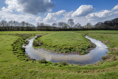 small stream winds its way through the green meadow and makes a sharp turn