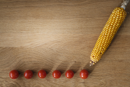 wooden table with tomatoes and  corn on the cob with copy spaceの写真素材